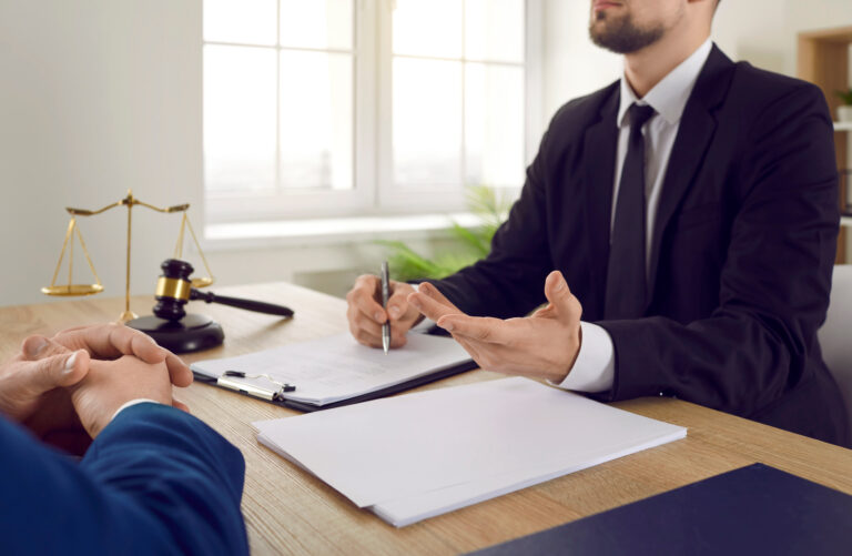 A personal injury solicitor sat at a desk explaining to a client how to sue a company for negligence