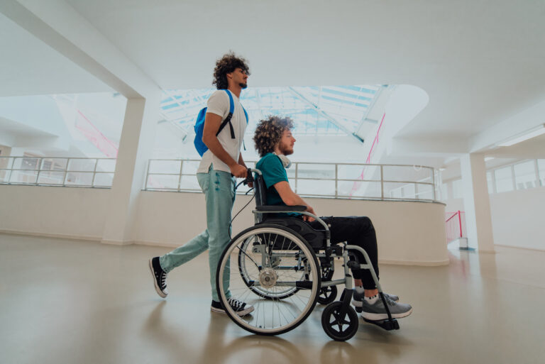 A friend pushes their other friend in their wheelchair
