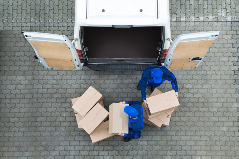 A pair of delivery workers unload boxes from a van
