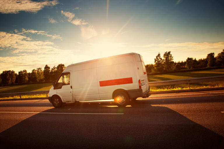 A delivery van drives on a road on a sunny day