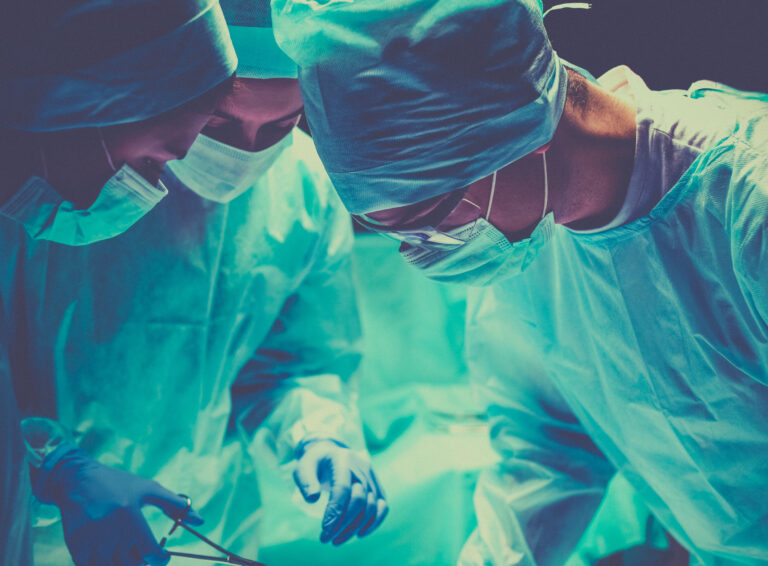Surgeons completing a hysterectomy on a woman.