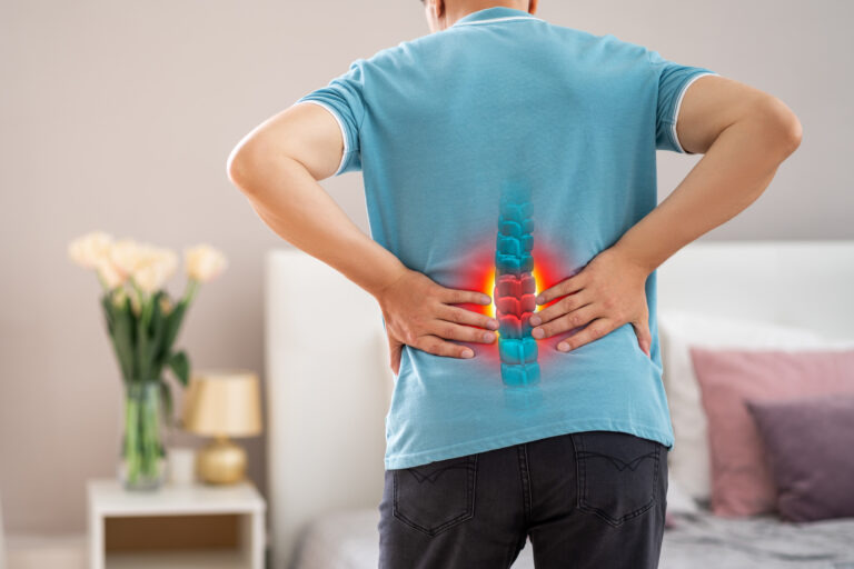 A man holding his back in pin after dislocating his spine. The injured area is highlighted in red.