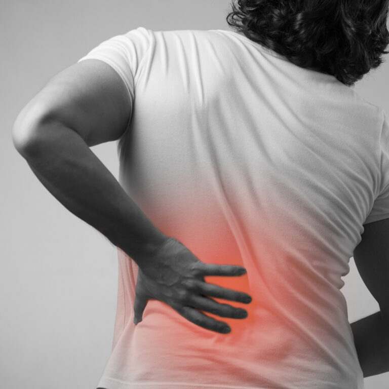 A person from behind clutching a radiating red patch on their side due to a manual handling back injury.