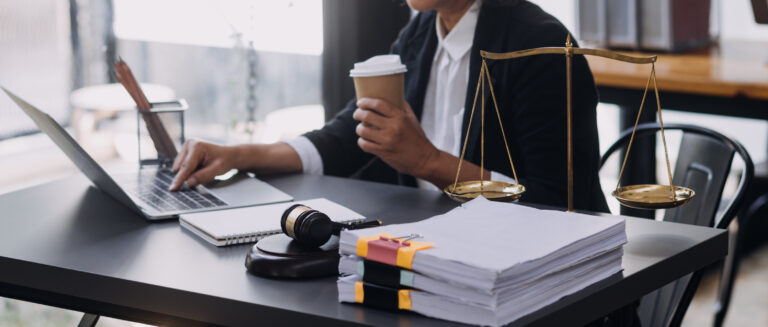 A personal injury lawyer drinking a coffee at her desk and reading up on herniated disc compensation payouts.