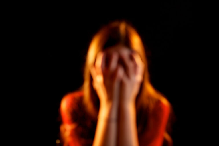 A woman holds her head in her hands due to suffering chronic pain syndrome