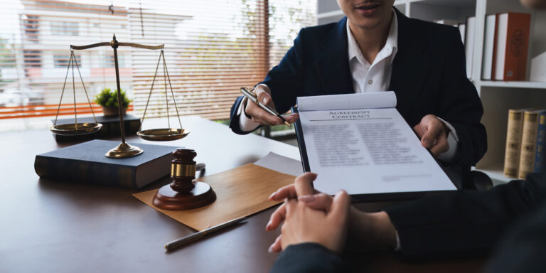 A solicitor at a desk with justice scales signs an after the event insurance policy